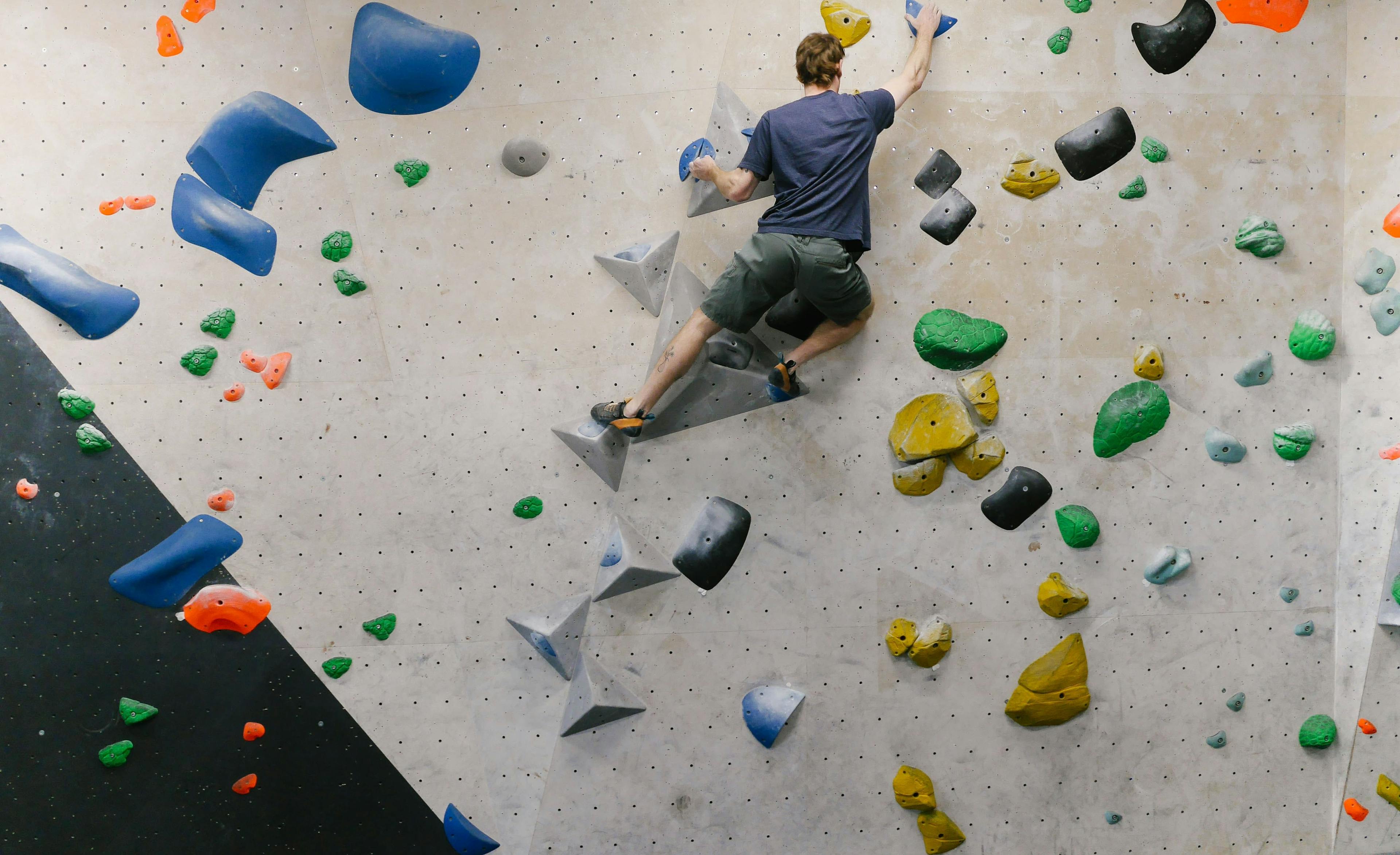 A man bouldering in a rock climbing gym