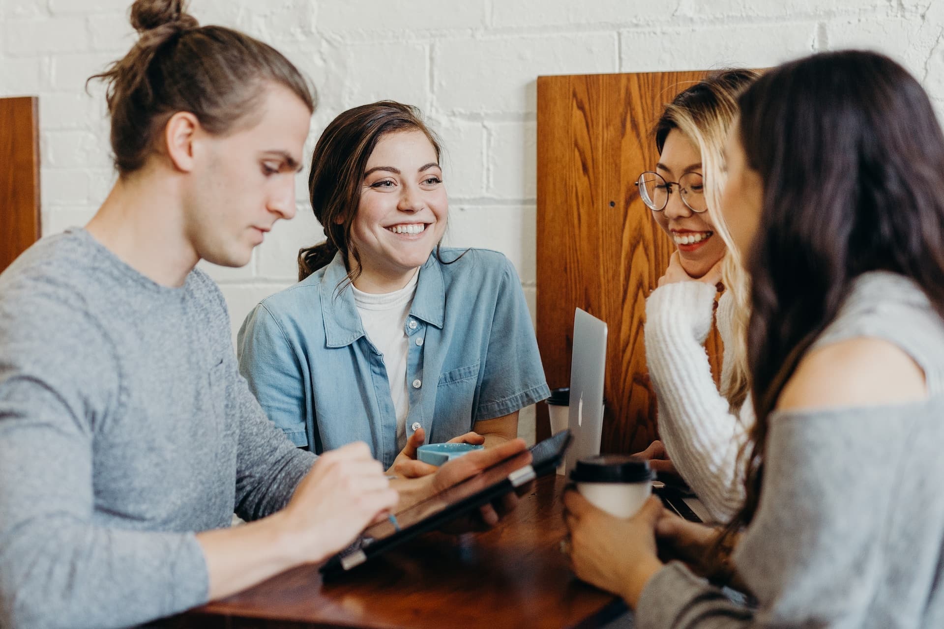 4 people sitting around a table with coffee, smiling and talking