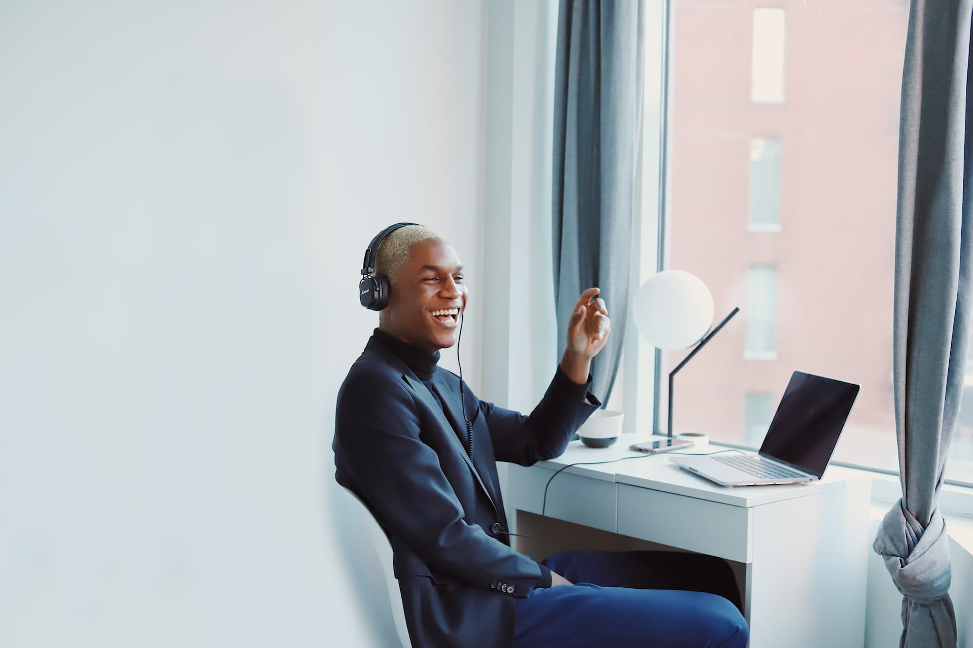 A man sitting at his desk with his headphones on, laughing.