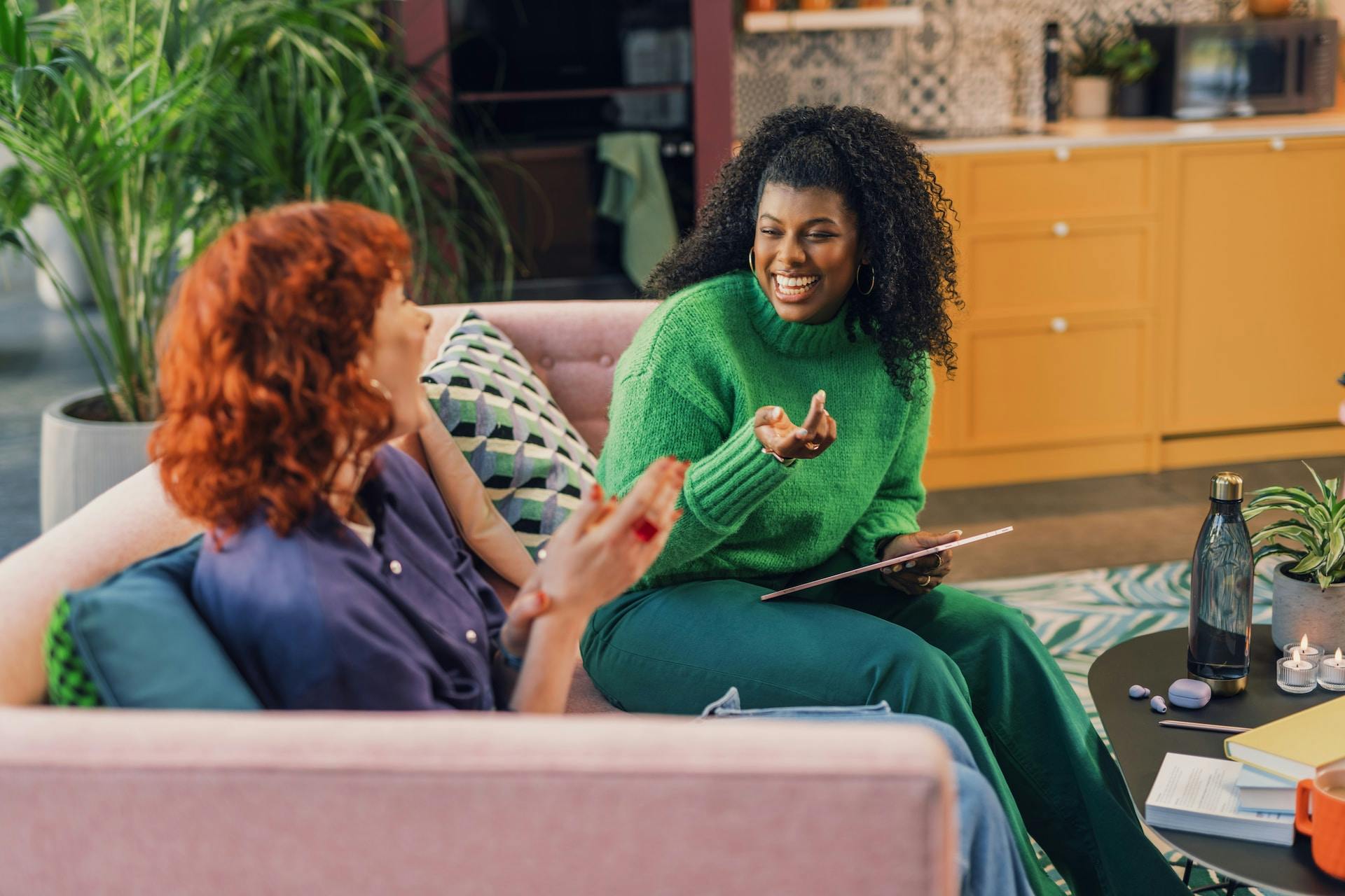 Two women sitting on a couch, talking and laughing
